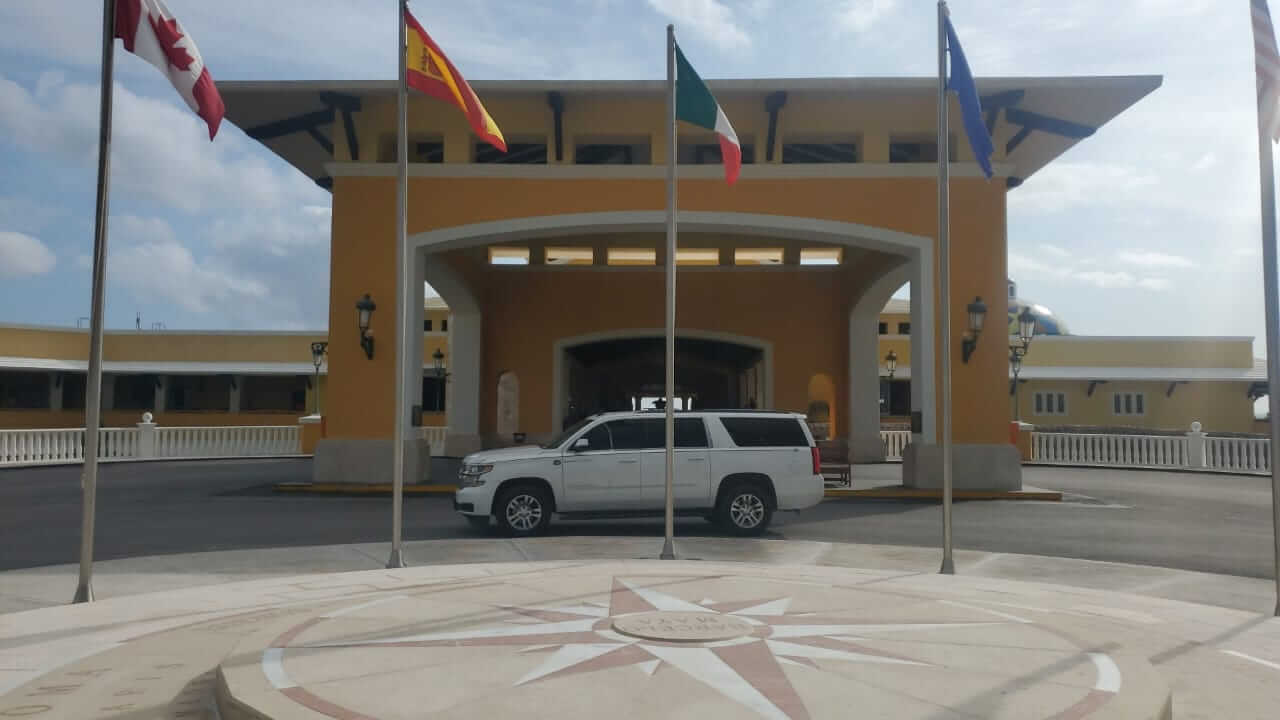 White Luxury SUV parked in front of hotel lobby with flags 