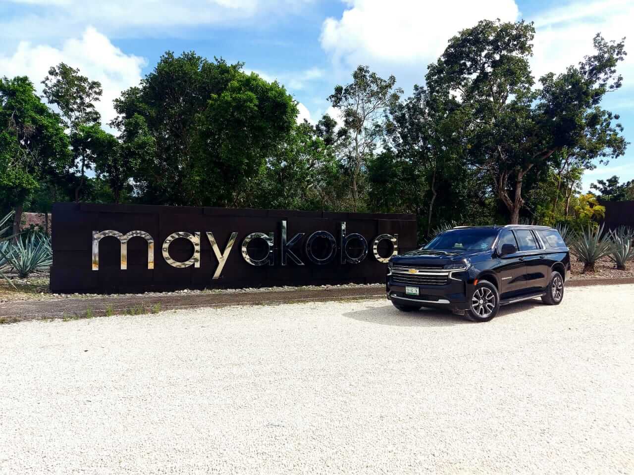 Camioneta negra de lujo estacionada por letrero de Mayakoba