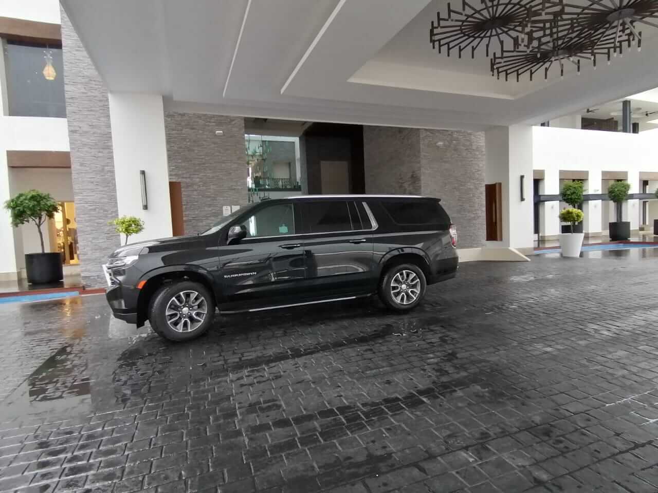 Camioneta negra de lujo en la entrada de un hotel con candelabros