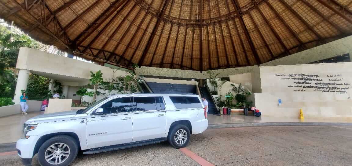 White Luxury SUV at palapa-roofed hotel entrance