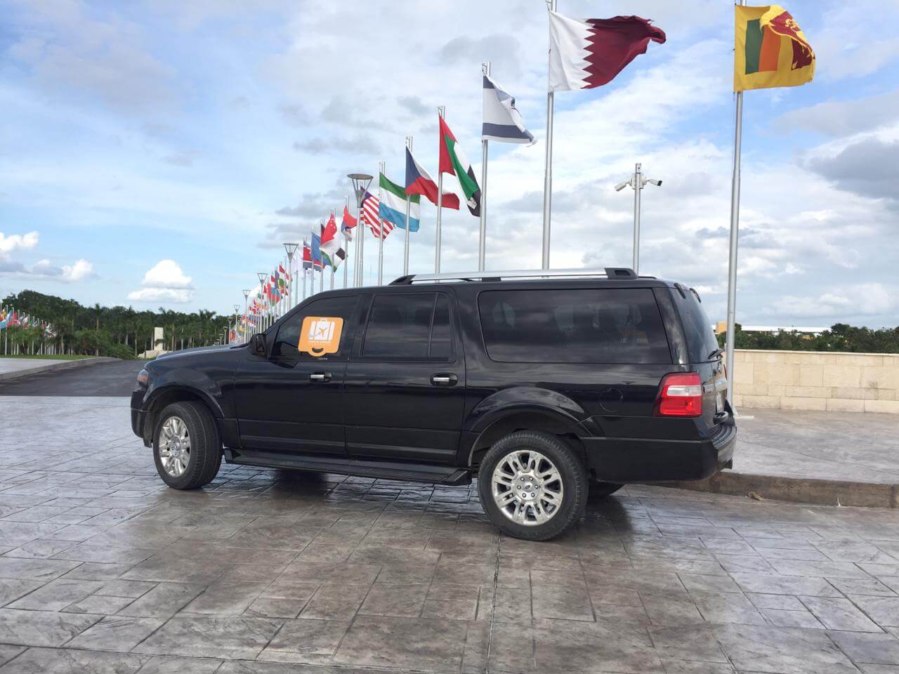 Black SUV parked by hotel entrance with several flags
